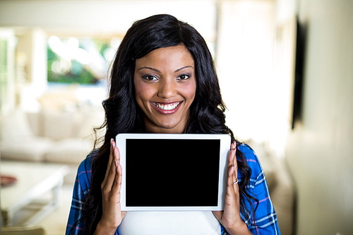 Portrait of young woman showing digital tablet at home