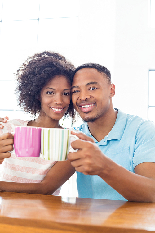 Portrait of happy couple toasting coffee mug at home