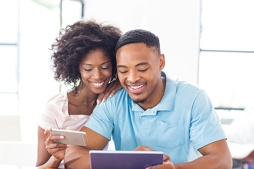 Happy couple using mobile phone and digital tablet at home