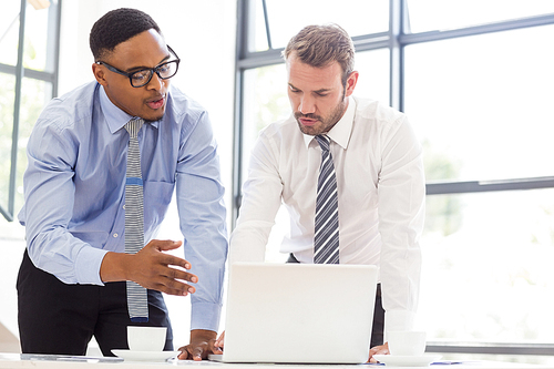 Businessmen using laptop at desk in office