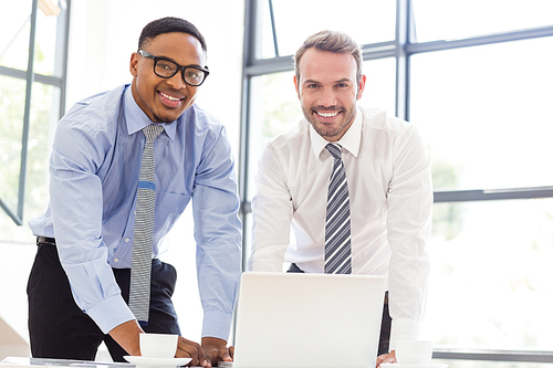 Portrait of businessmen using laptop at desk in office