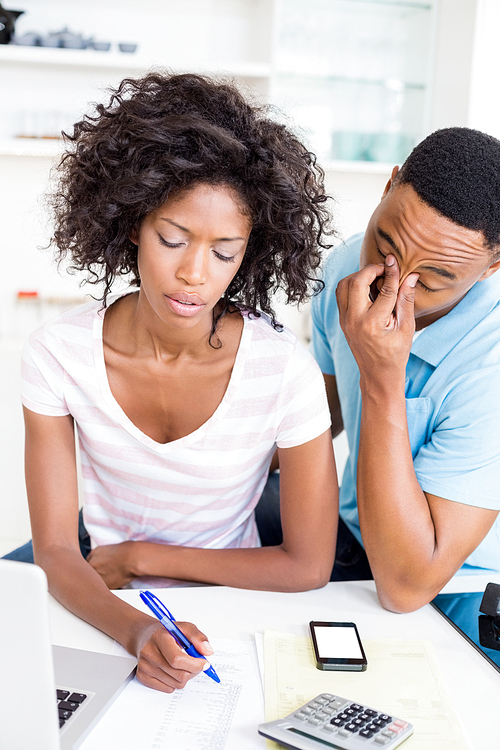 Worried young couple calculating bills at home