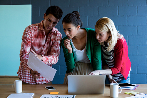 Colleagues discussing at desk in the office