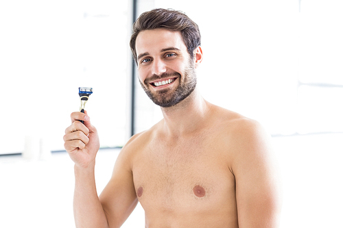 Portrait of man who is holding razor in the bathroom