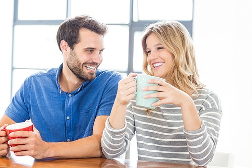 Young couple holding coffee mug in the kitchen