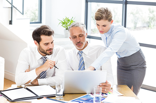 Business colleagues discussing office work on laptop in office