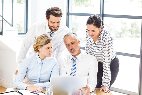 Business colleagues discussing office work on laptop in office