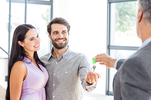 Real-estate agent giving house keys to couple in their new home