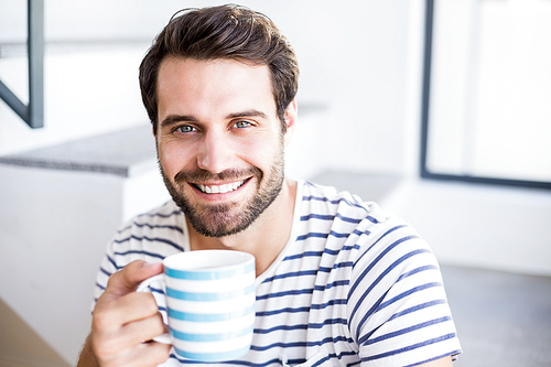 Portrait of happy man having cup of coffee at home