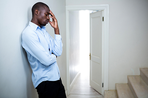 Tensed man leaning on wall at home