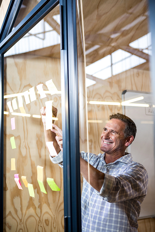 Man looking at sticky notes on window in the office