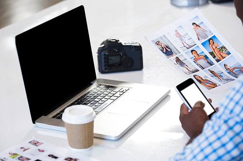 Man looking a chart with laptop and camera on desk in office