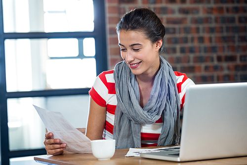 Woman looking at picture chart with laptop on table in office