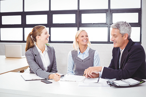 Business people smiling while discussing with client in meeting room