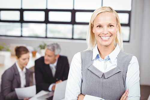 Portrait of happy businesswoman with business people sitting in background