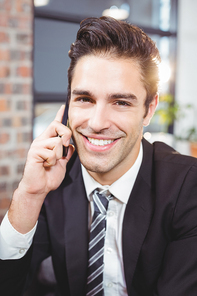 Close-up portrait of handsome businessman talking on mobile phone in office