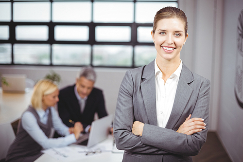 Portrait of businesswoman smiling while business people sitting in background
