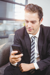 Close-up of handsome businessman using mobile phone in office