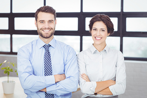 Portrait of happy business people with arms crossed standing in office