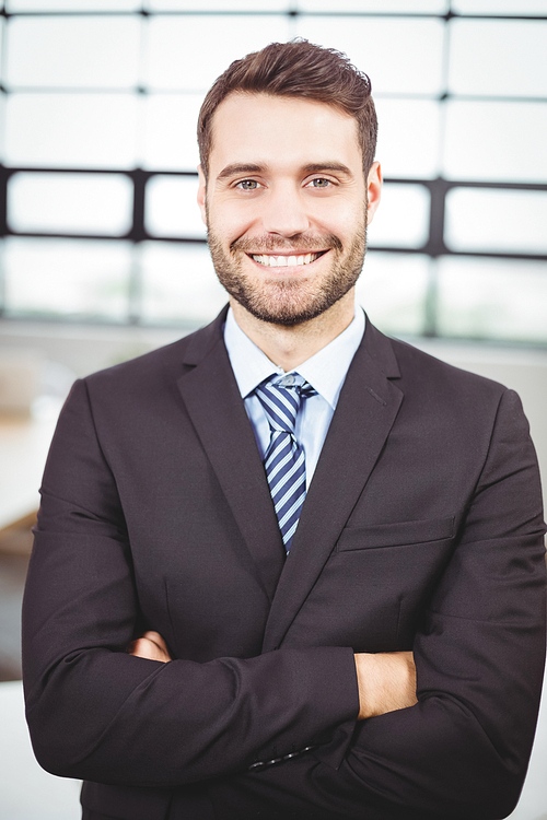 Portrait of confident businessman with arms crossed standing in office