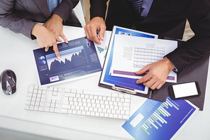 High angle view of business people discussing over graph while sitting at computer desk in office