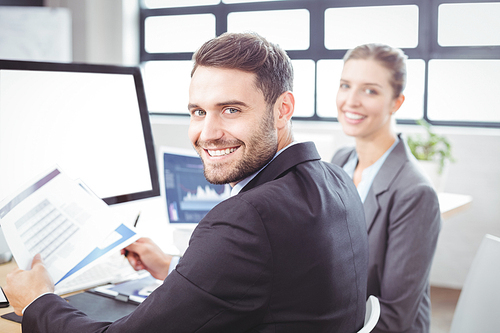Portrait of happy business people working at computer desk in office
