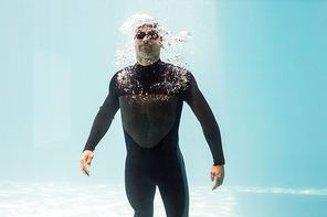 Young man wearing wetsuit while standing underwater