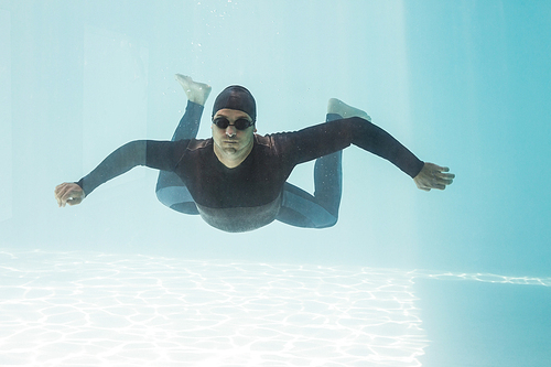 Young man with arms outstretched while swimming underwater