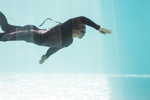 Young man with arm raised while swimming underwater