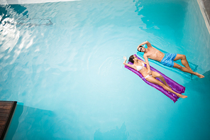 High angle view of couple relaxing on inflatable raft at swimming pool