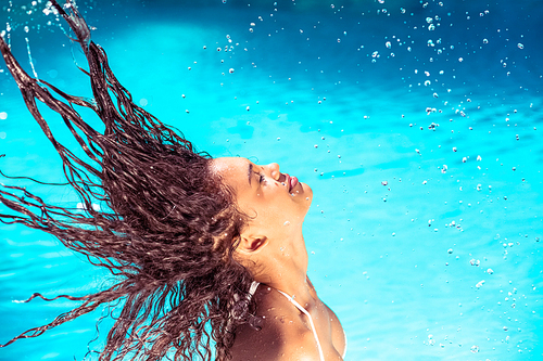 Beautiful woman tossing her wet hair in swimming pool