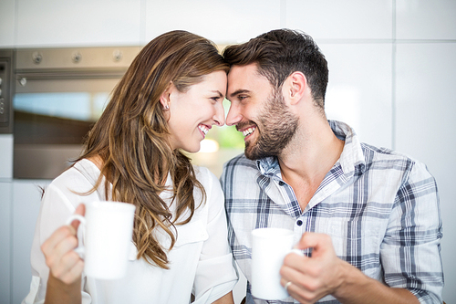 Close-up of happy couple with coffee mug looking at each other