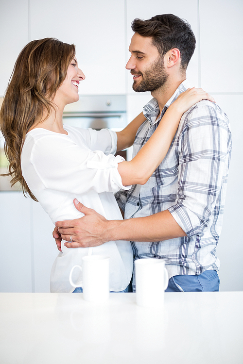 Young couple smiling while embracing by table at home