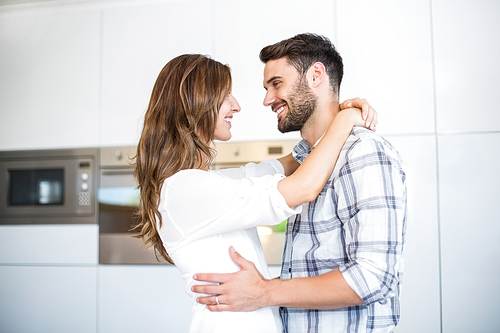 Happy young couple embracing in kitchen at home