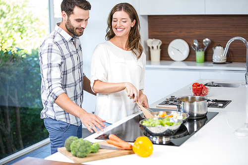 Man helping woman in cooking food at home