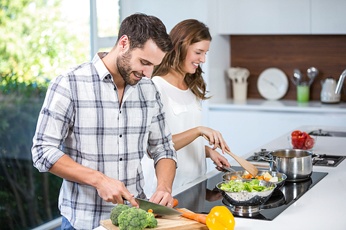 Happy young couple preparing food at kitchen counter