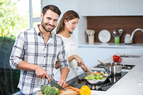 Happy young man helping woman in preparing food at home