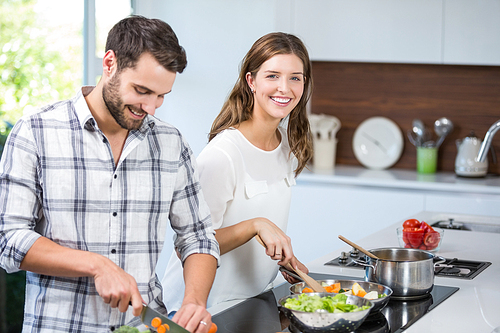 Cheerful young couple preparing food in kitchen at home