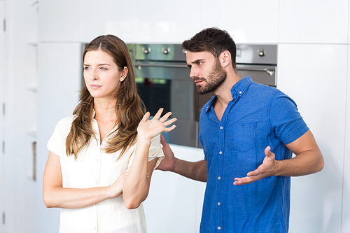 Man explaining to upset wife in kitchen at home