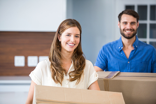 Portrait of couple holding boxes while moving house