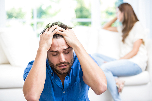 Tensed man sitting on floor after argument with wife at home