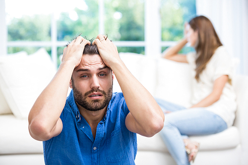 Upset man with hands on head after argument with wife at home