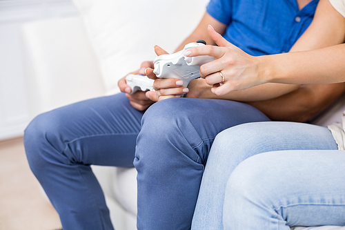 Mid section of couple playing video game at home