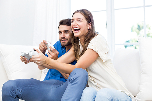 Couple playing video game while sitting on sofa at home