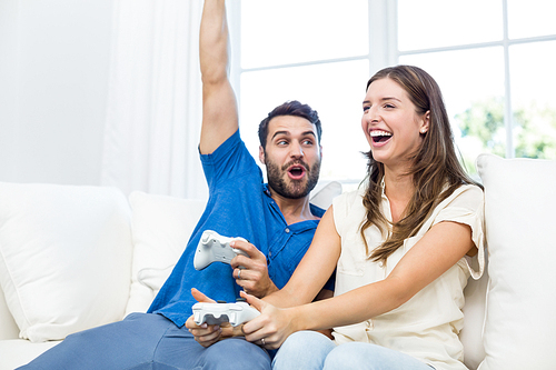 Couple enjoying video game on sofa at home