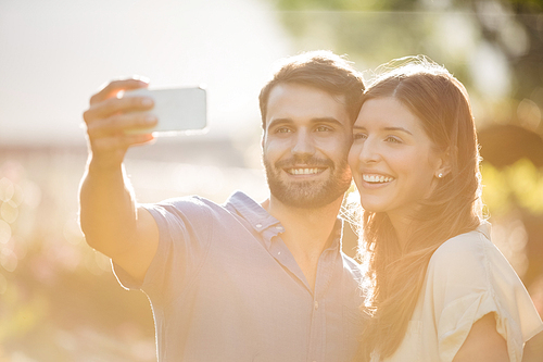 Happy couple clicking selfie with smart phone at park