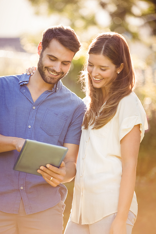 Couple looking at digital tablet at park