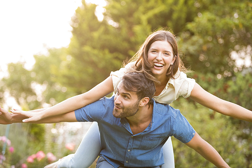 Happy man carrying woman on back at park