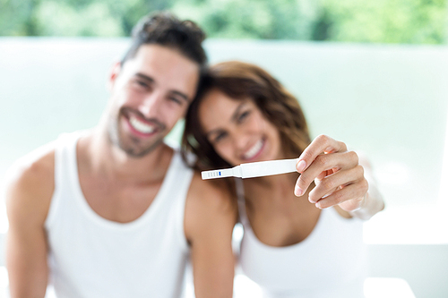 Portrait of happy couple showing pregnancy kit