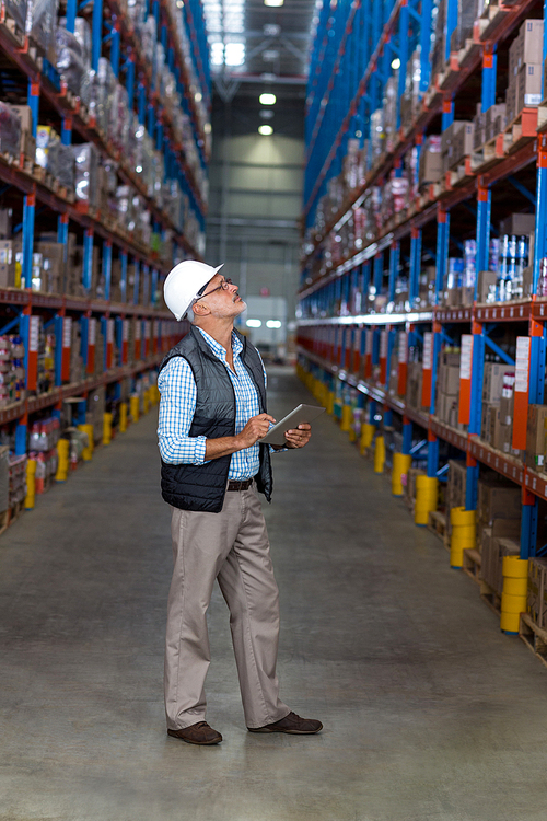 View of worker is looking shelves and holding a clipboard in a warehouse